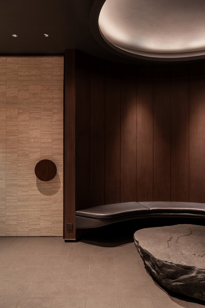 Detail of sliding timber door with circular handle beside curved seating and stone table