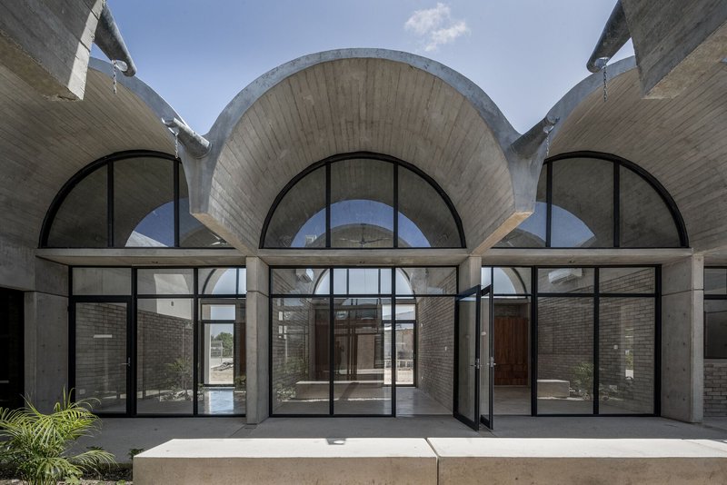 Symmetrical facade showing three arched openings with concrete horizontal beam under vaulted shells