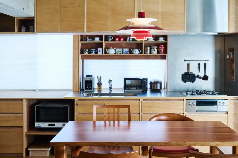 Kitchen with light oak cabinetry, open shelving, and a red pendant light above the workspace