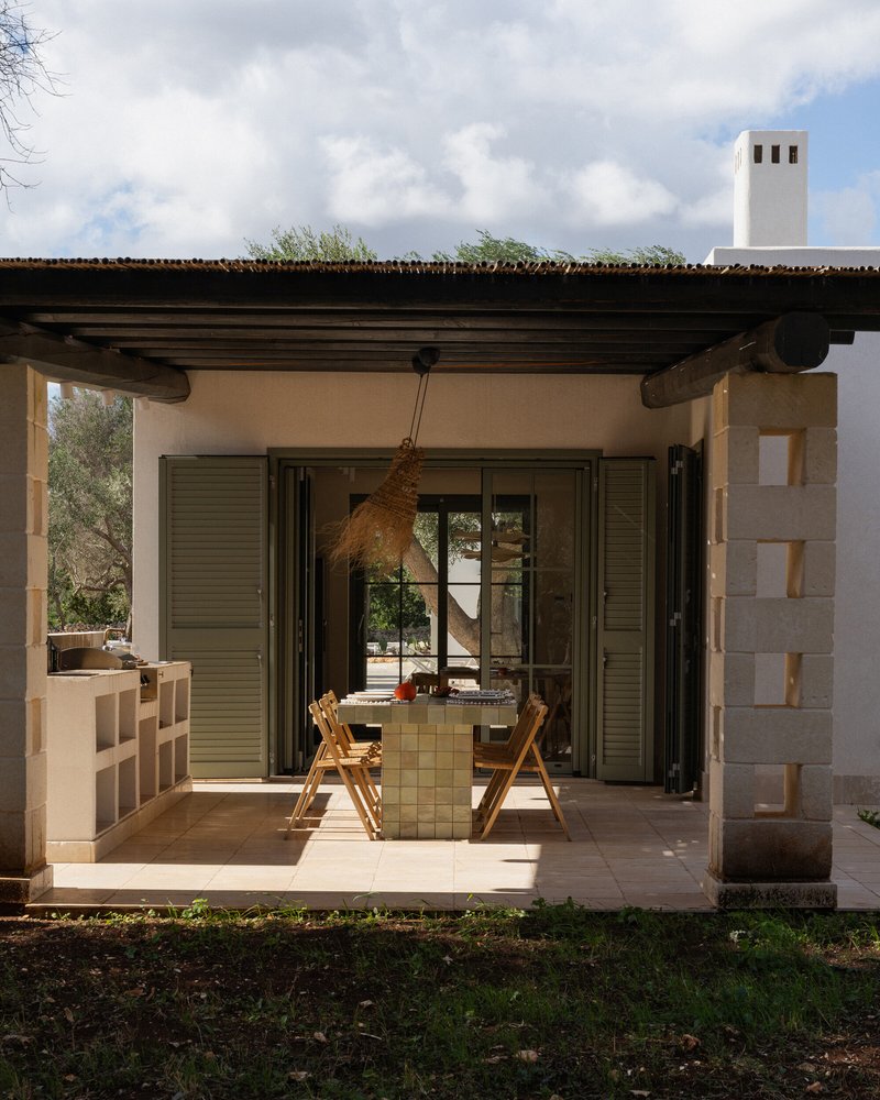 Covered terrace with timber beam roof and folding glass doors opening to an interior dining area