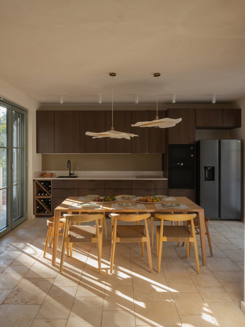 Dining area with dark timber cabinetry and driftwood pendant lights above a timber table