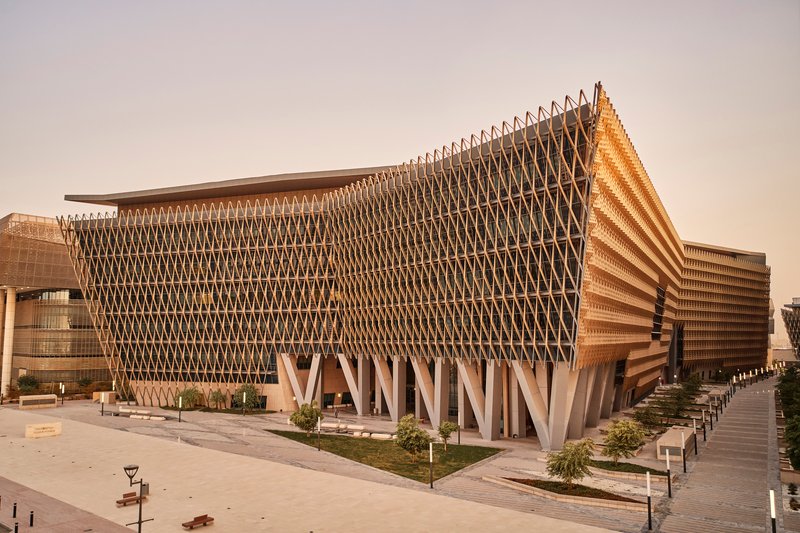 Corner view of the parametric timber lattice facade supported by angular concrete columns in afternoon light