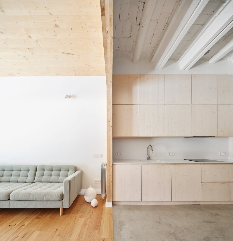 Open-plan kitchen and living area with plywood cabinetry, exposed timber beams and polished concrete floor