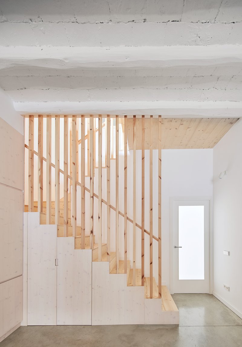 Timber staircase with vertical slat balustrade and plywood storage cabinets beneath the treads