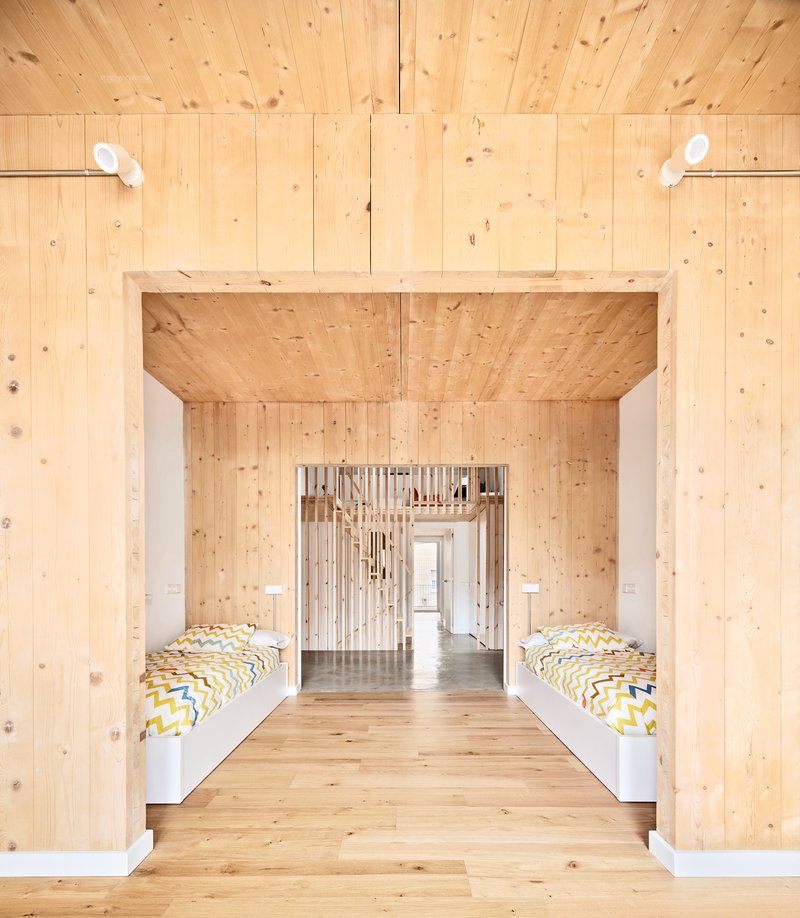 Symmetrical bedroom with timber-lined portal and twin beds under exposed plank ceiling