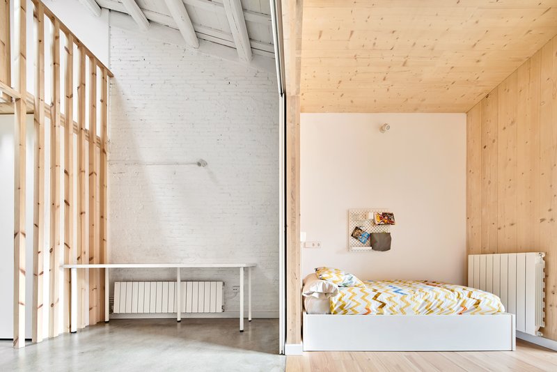 Sleeping alcove with single bed beside timber slat screen and polished concrete floor