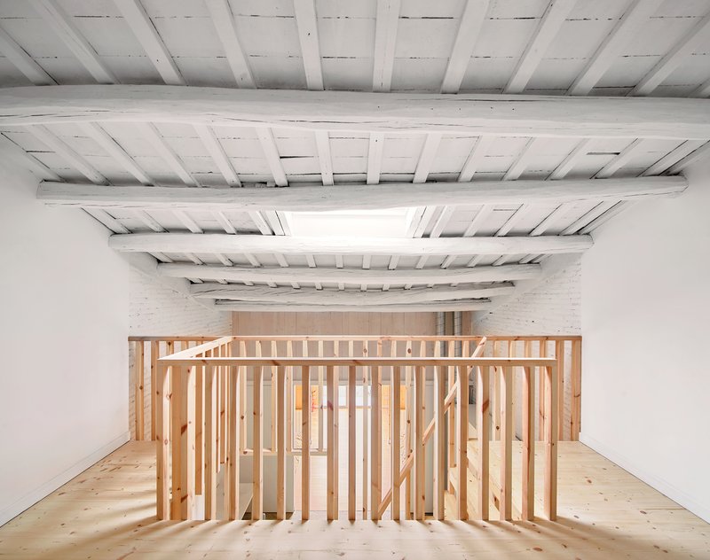 Slatted timber guardrail wrapping the upper level beneath exposed whitewashed joists and a linear skylight
