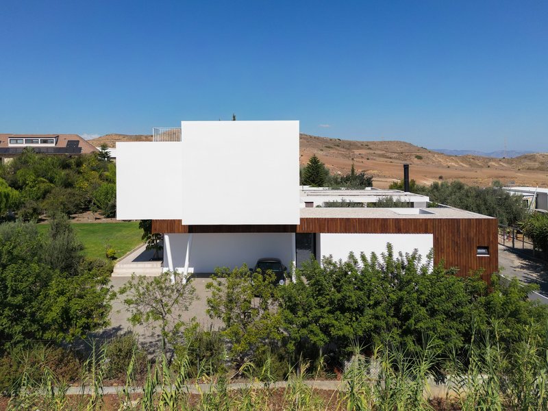 Street-facing elevation showing white render and vertical timber cladding above a planted garden with shrubs and grasses