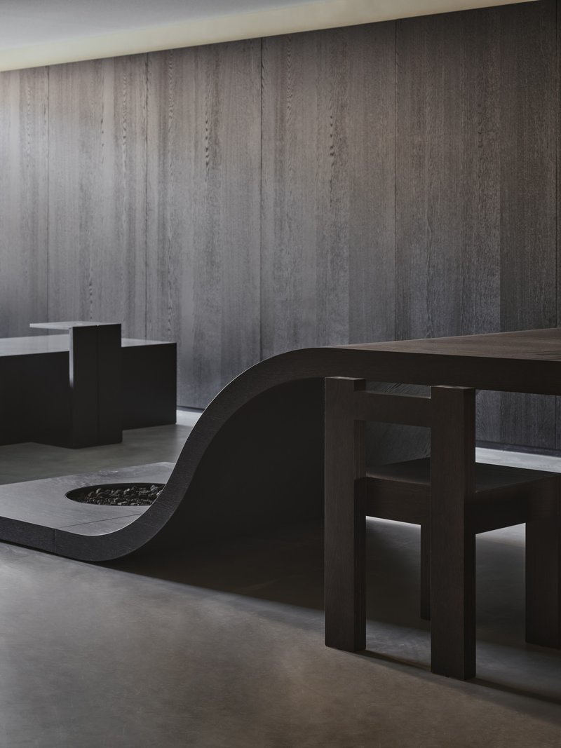 Sculptural black seating elements against a vertically ribbed concrete wall