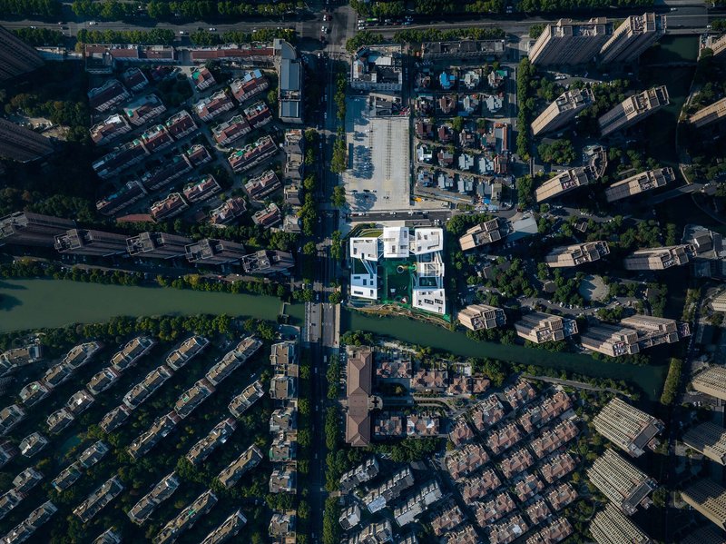 Drone view of the compound surrounded by waterways and tiled-roof residential neighborhoods at midday