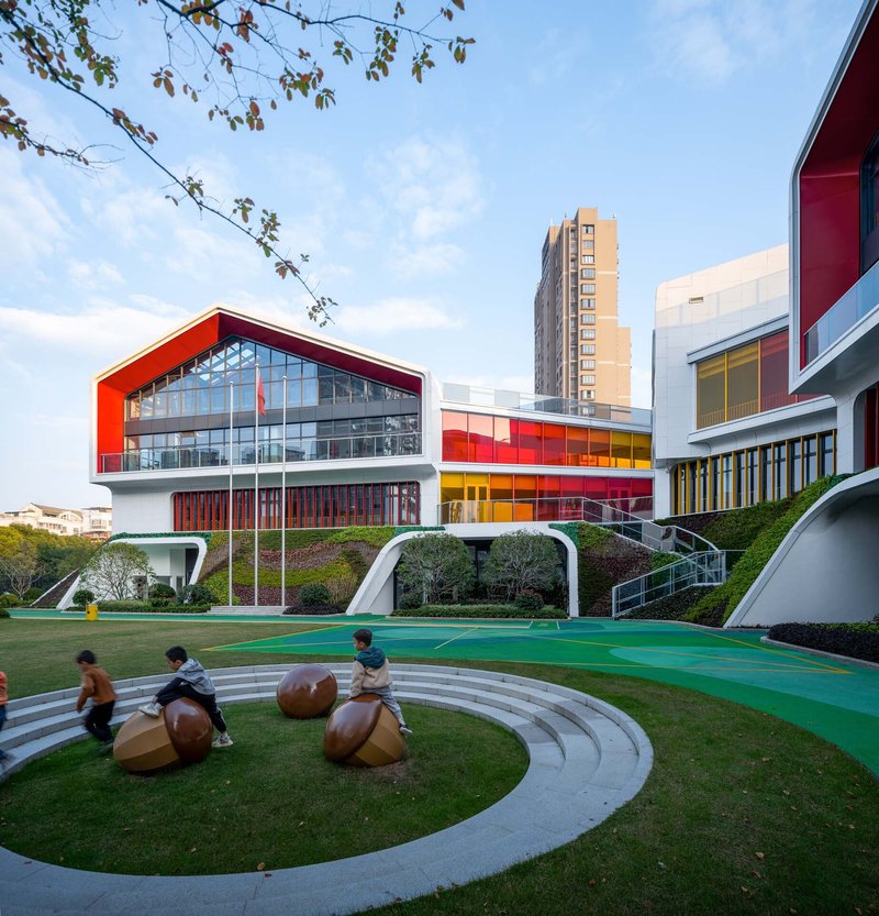Outdoor play area with circular stepped seating and wooden climbing spheres beneath spring tree branches