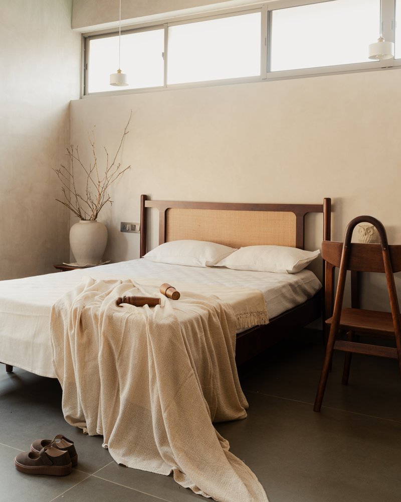 Bedroom with timber and cane headboard under a high clerestory window with soft daylight