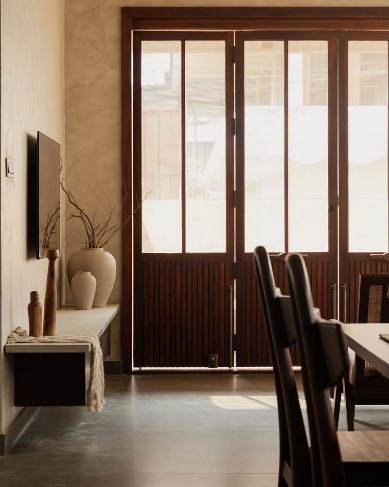 Timber-framed glass doors with vertical slat panels filtering daylight into the dining area
