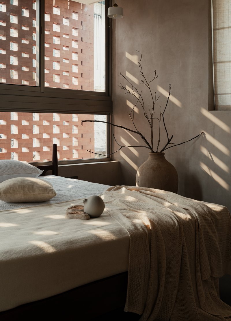 Bedroom window with chequered brick screen casting dappled shadows across the bed