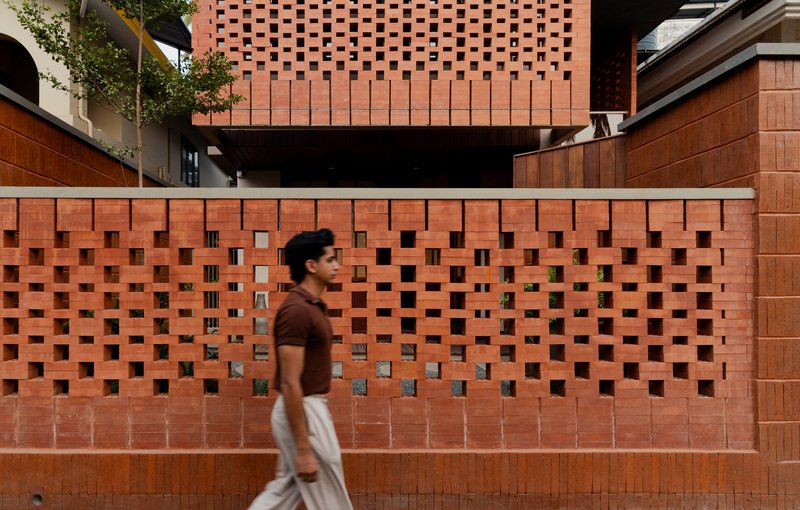 Person walking past the chequered brick boundary wall along the street level terrace