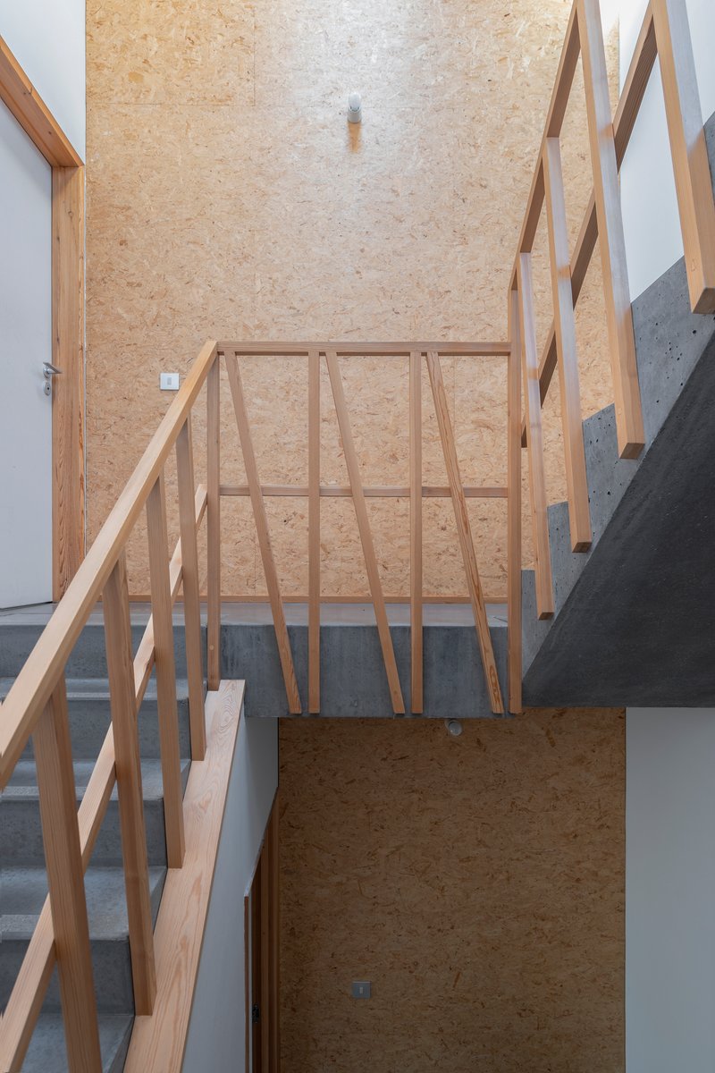 Top-down view of stair landing with exposed oriented strand board walls and timber railing
