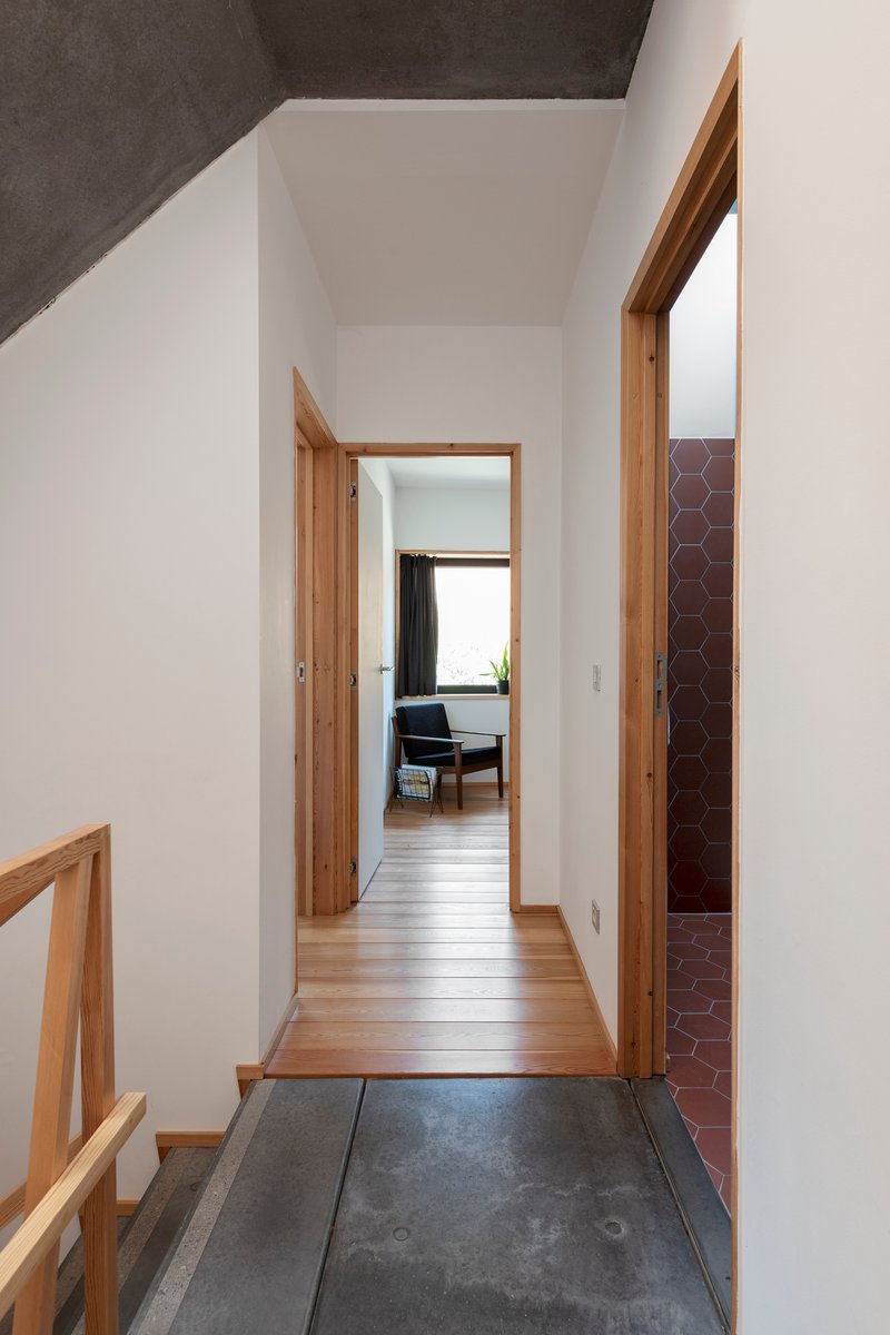 Entry hallway with dark stone flooring transitioning to timber, white walls and timber-framed doorways