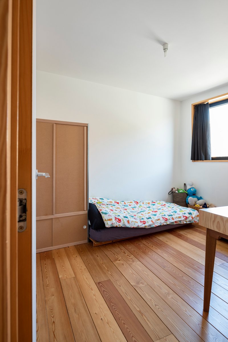 Bedroom with timber flooring, built-in wardrobe and window with dark curtain in natural light