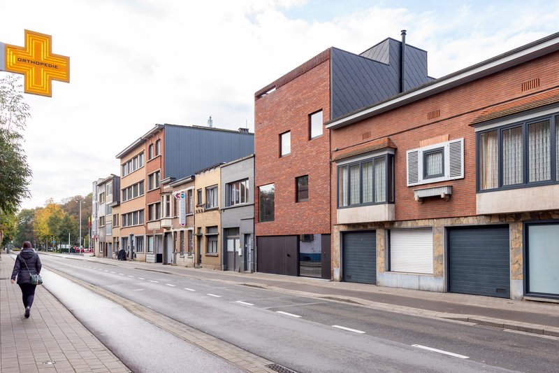 Street view of mixed brick and corrugated metal facades with a pedestrian crossing in autumn