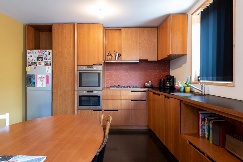 Kitchen with oak cabinetry and a terracotta hexagonal tile backsplash under recessed lighting