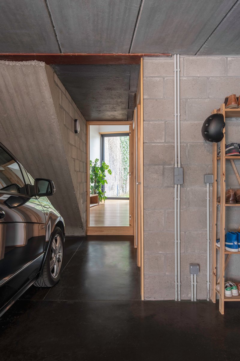 Garage interior with concrete block walls, exposed ceiling and a doorway framing garden greenery