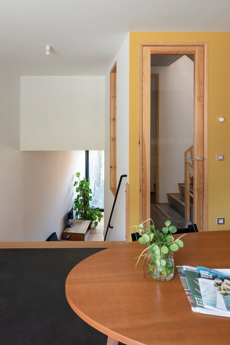 Round timber dining table with view through doorway to planted stairwell below
