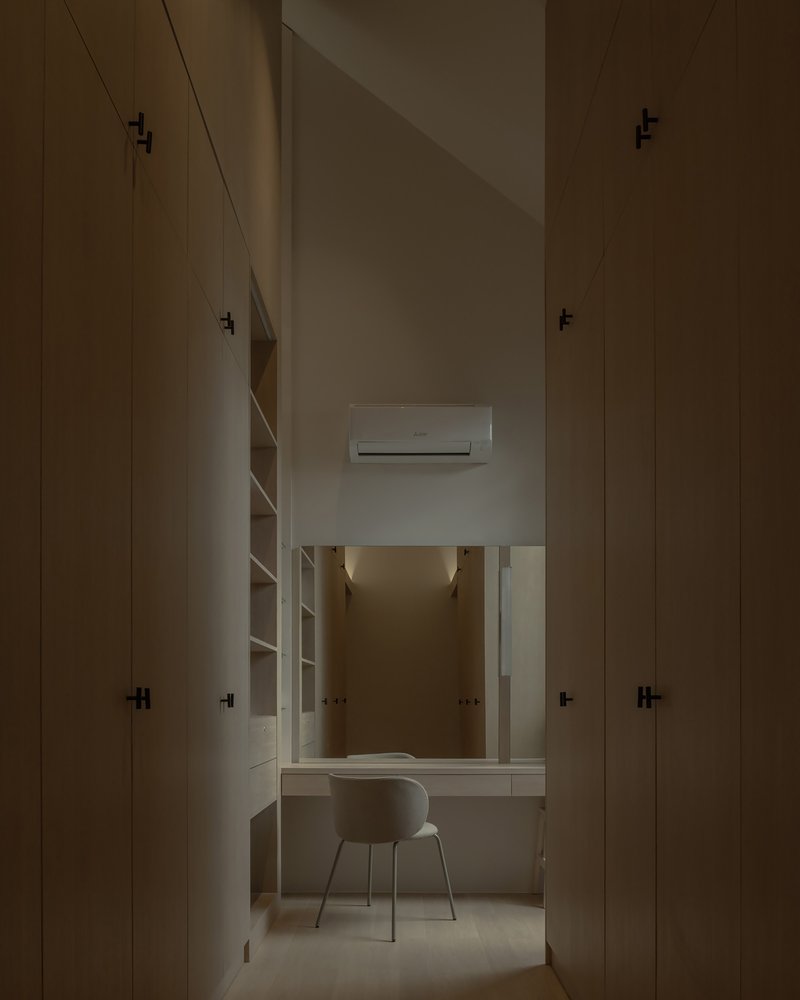 Narrow study alcove with built-in desk and shelving flanked by tall plywood storage cabinets in soft light