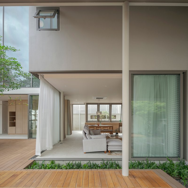 View through courtyard to living and dining space with sheer curtains and planted beds