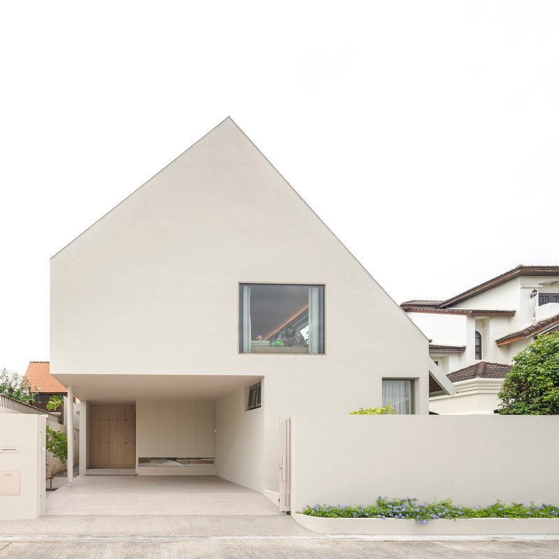 White plastered street facade with gabled profile and covered carport under overcast sky