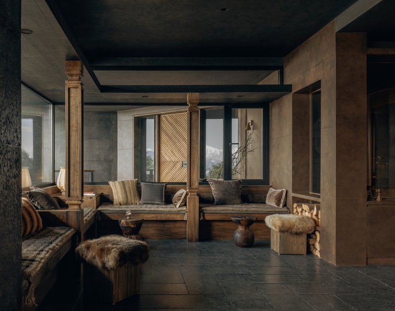 Lounge space with carved wooden columns, dark ceiling beams, and mountain views through tall windows