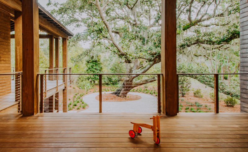 Interior deck with exposed timber columns and cable railing overlooking live oak and planted courtyard