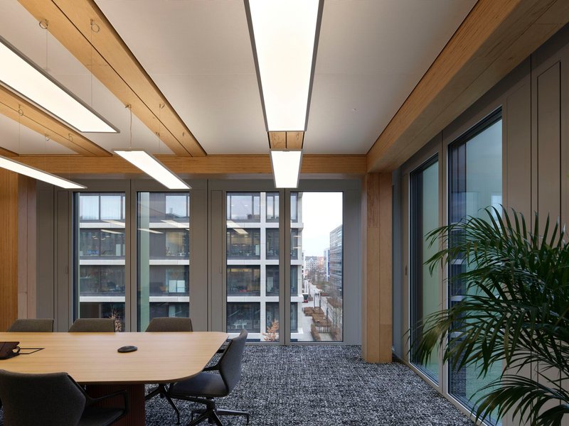 Meeting room with corner glazing and timber beam ceiling framing views of neighboring buildings