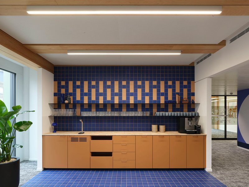 Kitchenette with blue and yellow patterned tile backsplash above timber cabinetry and open shelving