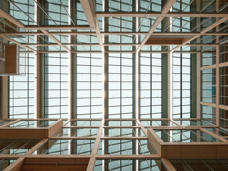 Upward view into a timber-framed atrium with gridded translucent panels flooding the space with diffused light