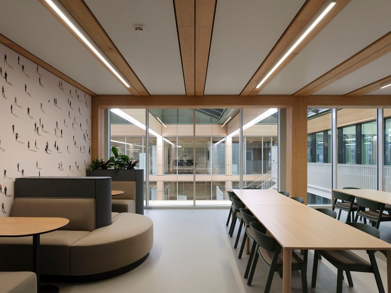 Interior lounge space with circular seating overlooking a glazed atrium with visible levels beyond
