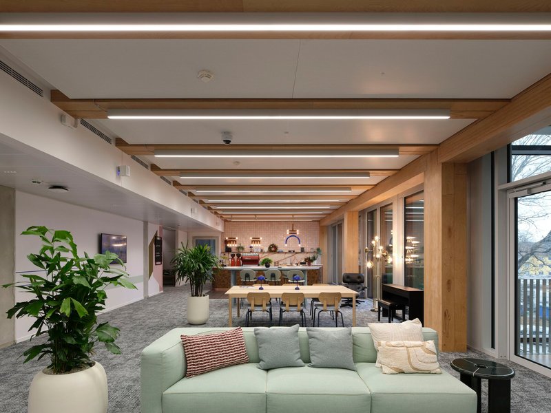 Common area with exposed timber beams and integrated lighting above seating and dining zones