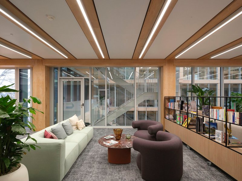 Seating area with timber-framed glazing overlooking a central staircase within the atrium