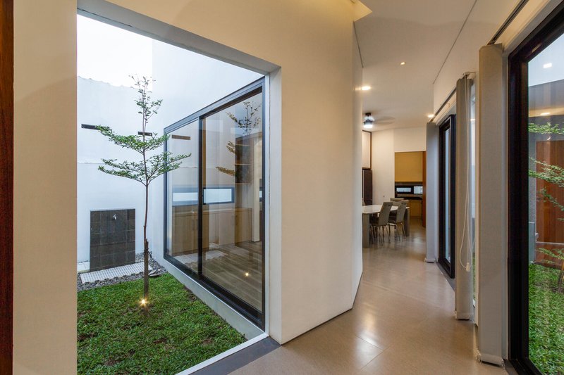 Hallway with pivoting glass wall opening to planted courtyard and polished concrete floor