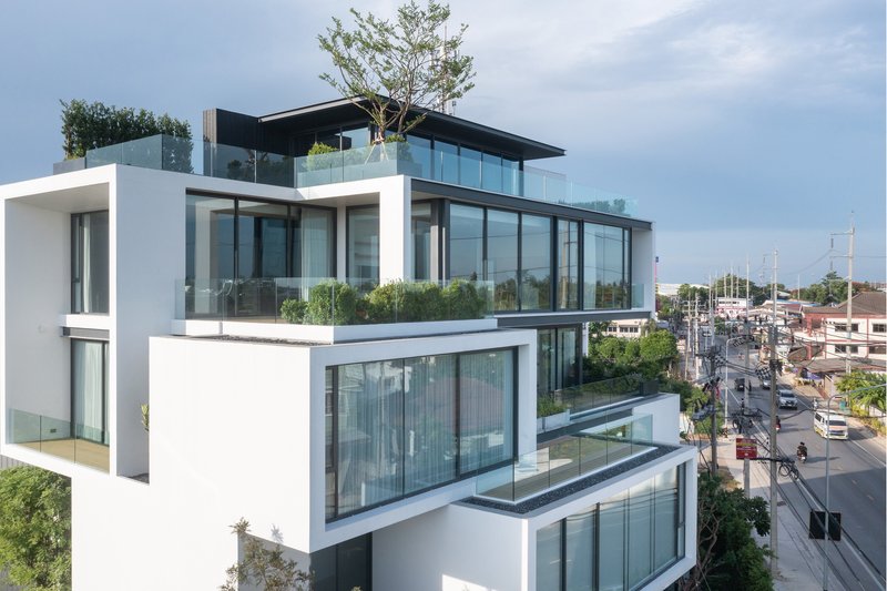 Stacked white volumes with glass walls and planted terraces overlooking the street below