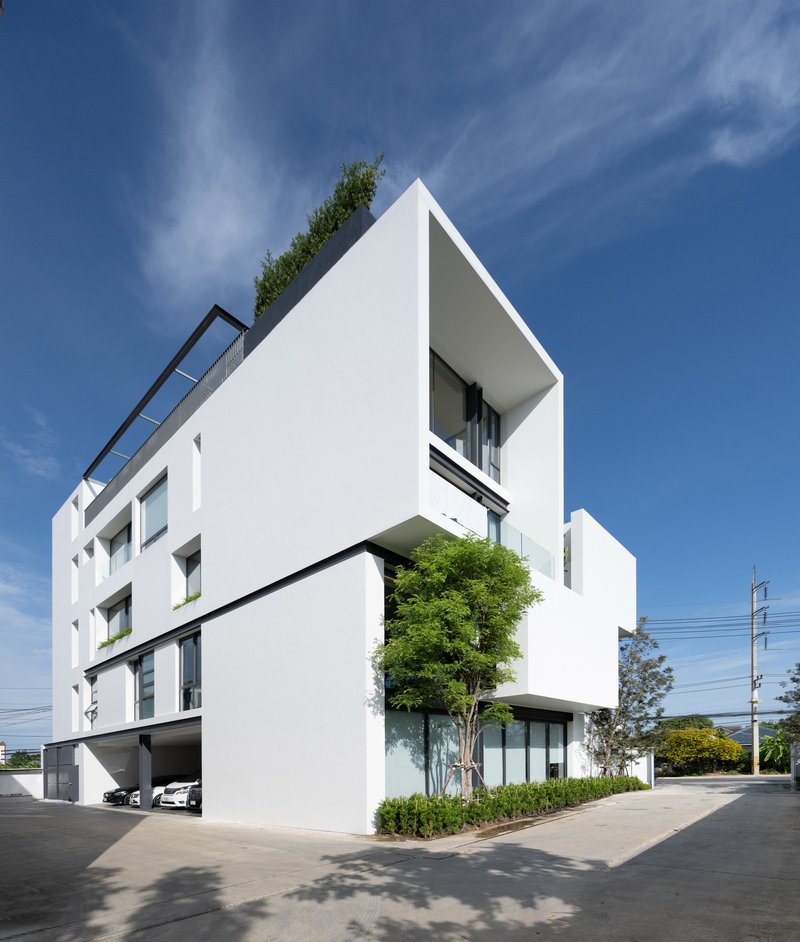 White stucco facade with cantilevered volumes and rooftop garden under a clear blue sky