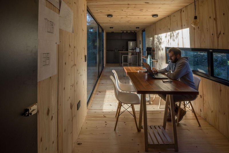 Person working at a timber table in the pine-lined interior with ribbon windows on both sides