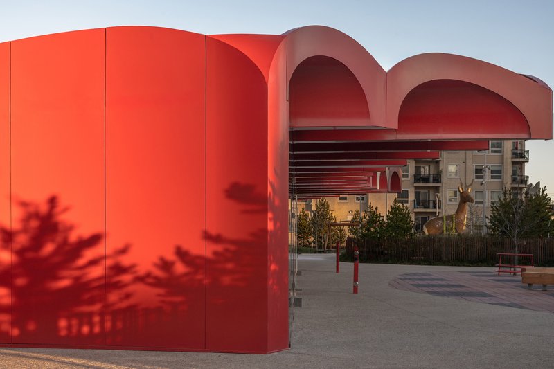 Red paneled wall with tree shadow cast across the surface at dusk