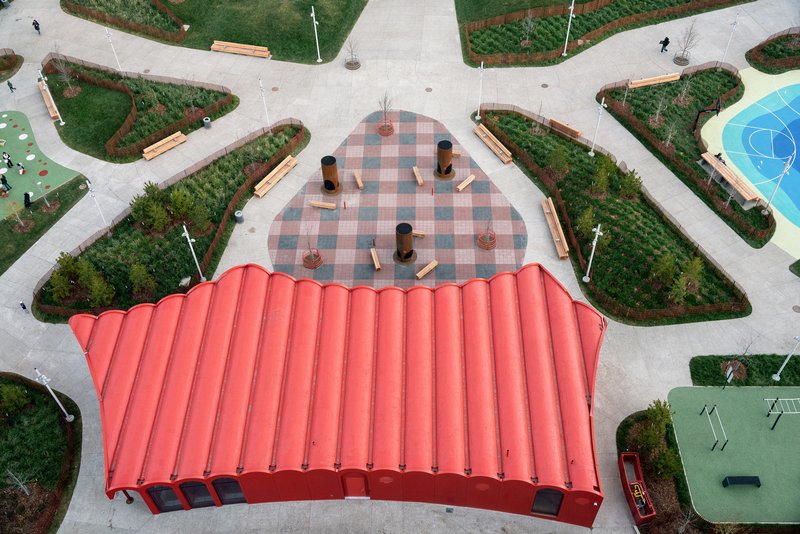 Aerial view of the undulating red roof sheltering a chequered plaza surrounded by planted garden beds