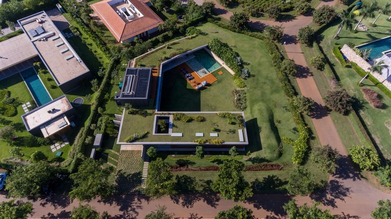 Aerial view of rectangular volumes arranged around courtyards and a swimming pool surrounded by lawn