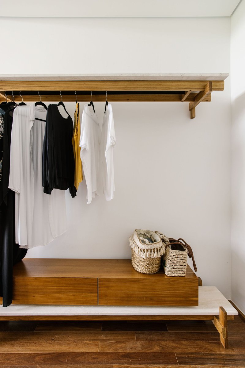 Wall-mounted timber shelf with hanging rail and low storage bench in the dressing area