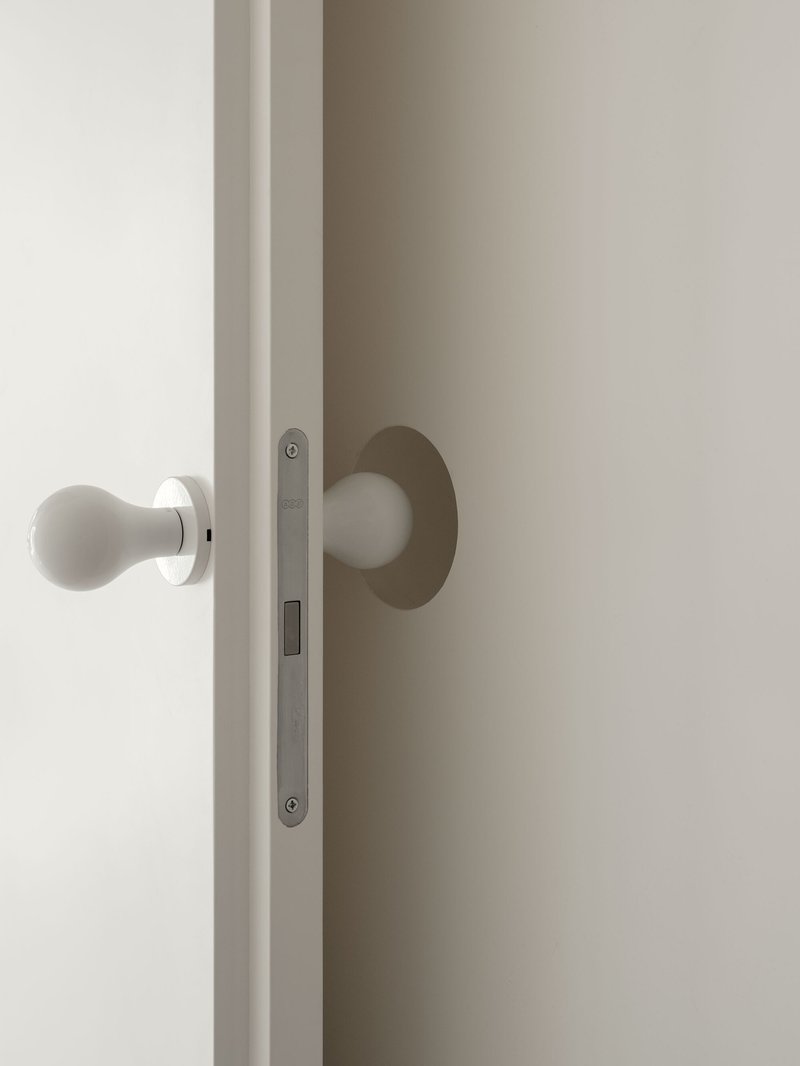 Detail of white spherical door handle with brushed metal backplate and mortise lock