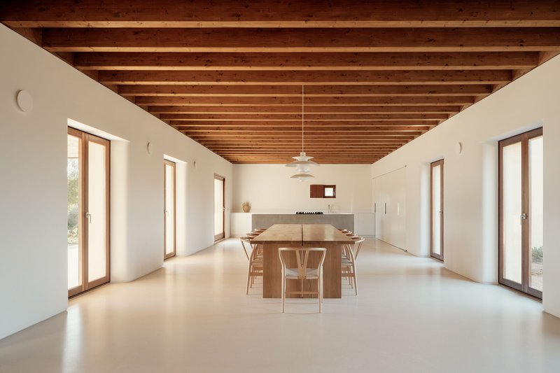 Open-plan dining space with exposed timber ceiling joists and timber-framed glazed doors on both sides