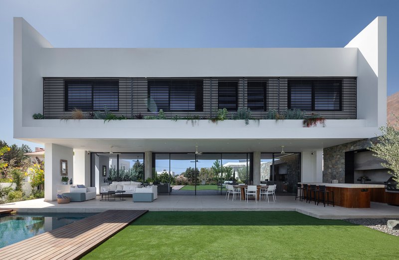 Garden facade showing horizontal louvers on the upper balcony above the open living terrace and pool
