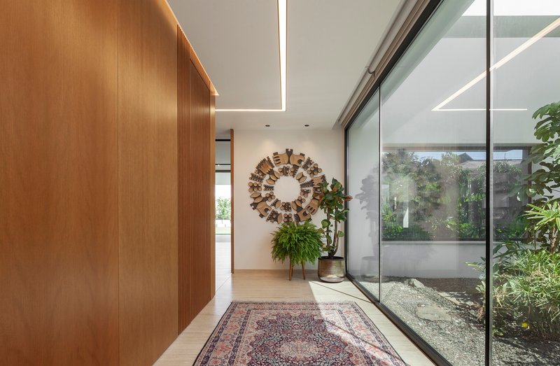 Entry hall with timber wall paneling and glass wall overlooking internal planted courtyard