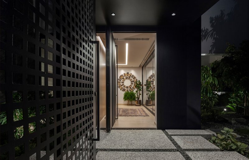 Entry path with perforated screen wall and planted garden beds illuminated at night
